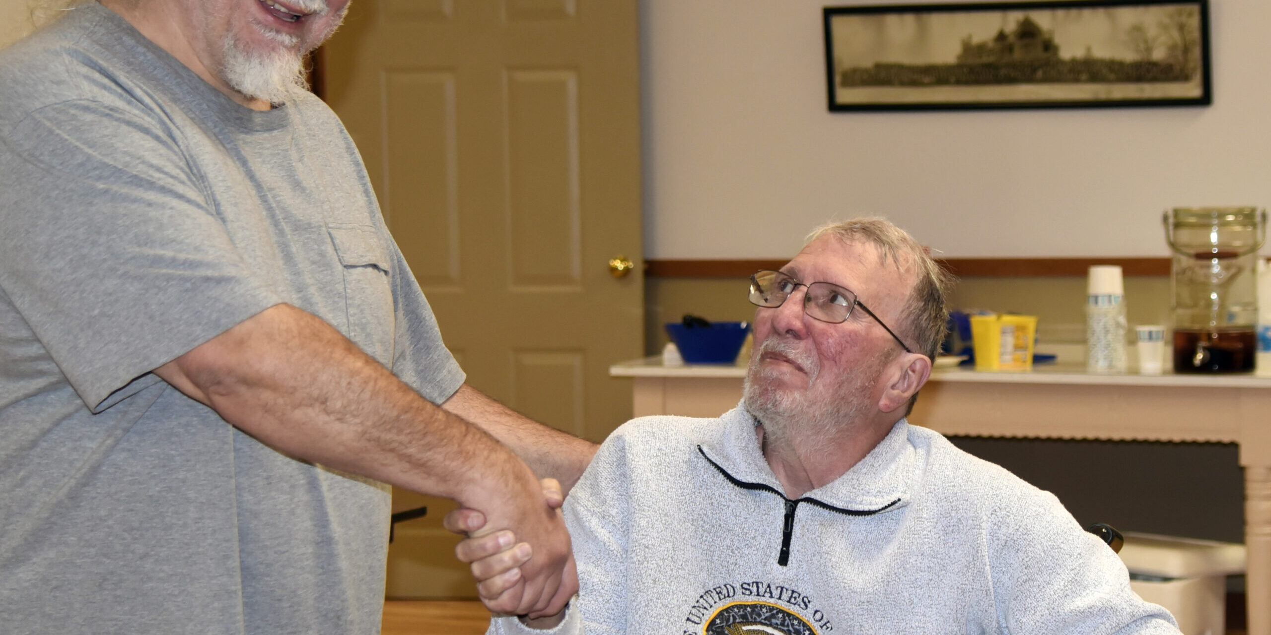 Winner Frank Austin, seated center-right, shakes hands with board member Bret Greenwood, standing, left.