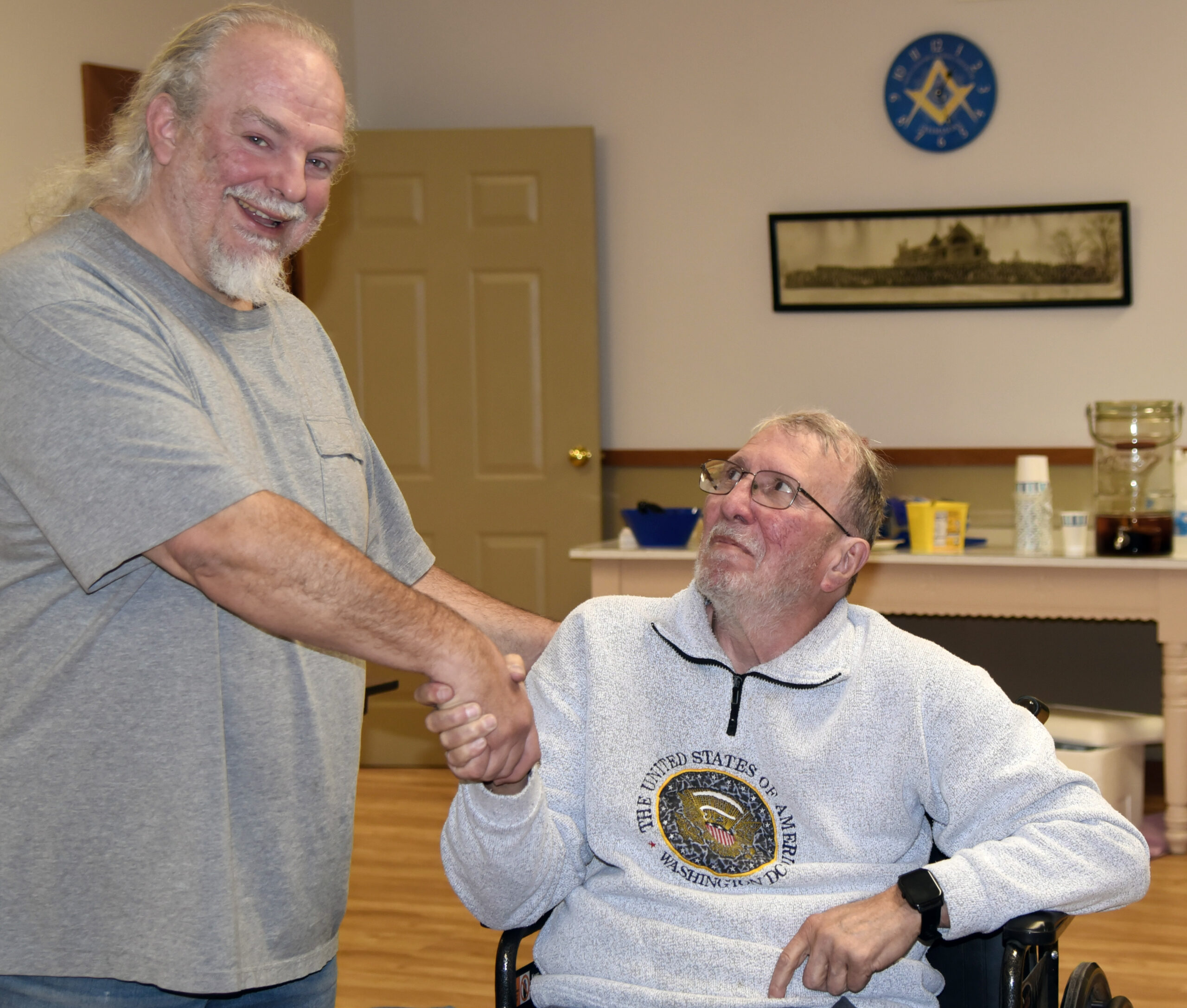 Winner Frank Austin, seated center-right, shakes hands with board member Bret Greenwood, standing, left.